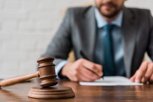 Close-up view of wooden hammer and judge in a suit working.