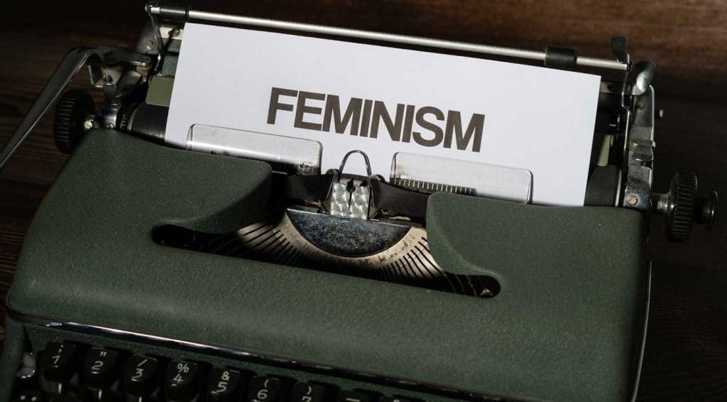 A typewriter holding a paper with the word feminism